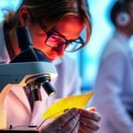 Postdoc working with glowing plant in lab setting.