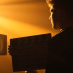 Filmmaker holding a clapperboard with projector light.