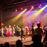 Performers in costumes on a colorful festival stage.